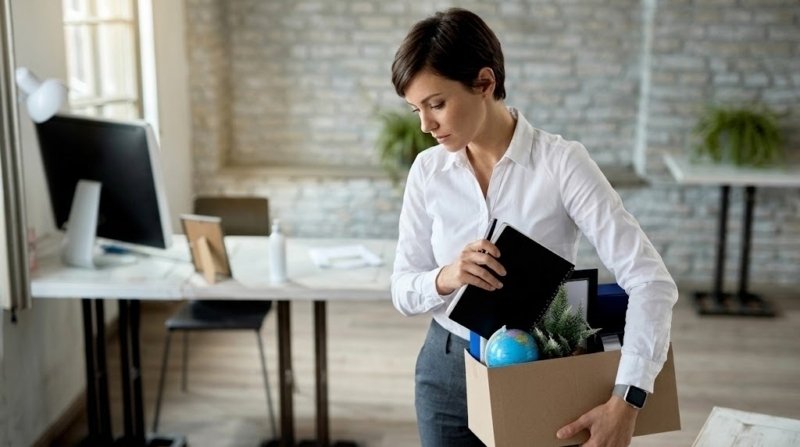 Mujer guardando sus objetos personales en una caja de cartón al dejar su escritorio, representando la renuncia a un trabajo sin tener otro empleo asegurado